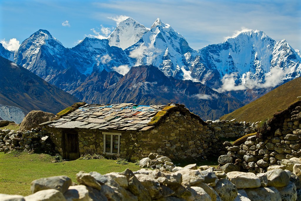 A traditional Himalayan stone house beneath snow-covered mountains
